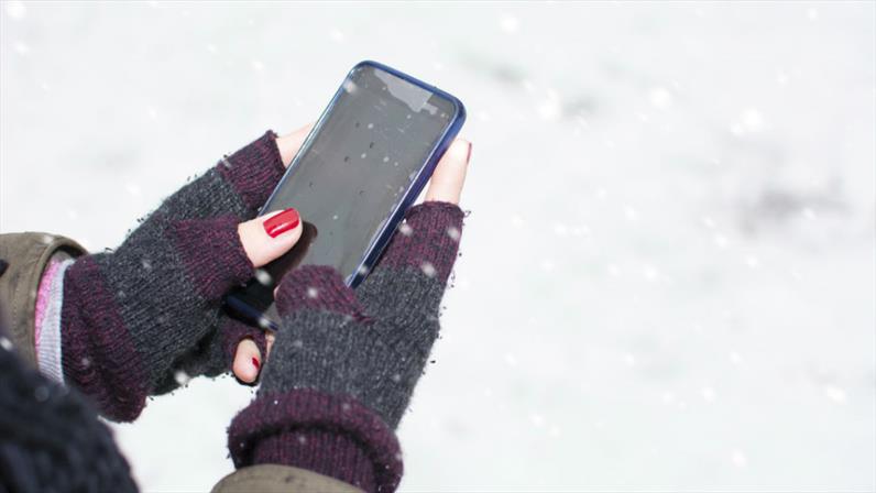 گوشی در دست برای حفظ دما در هوای برفی